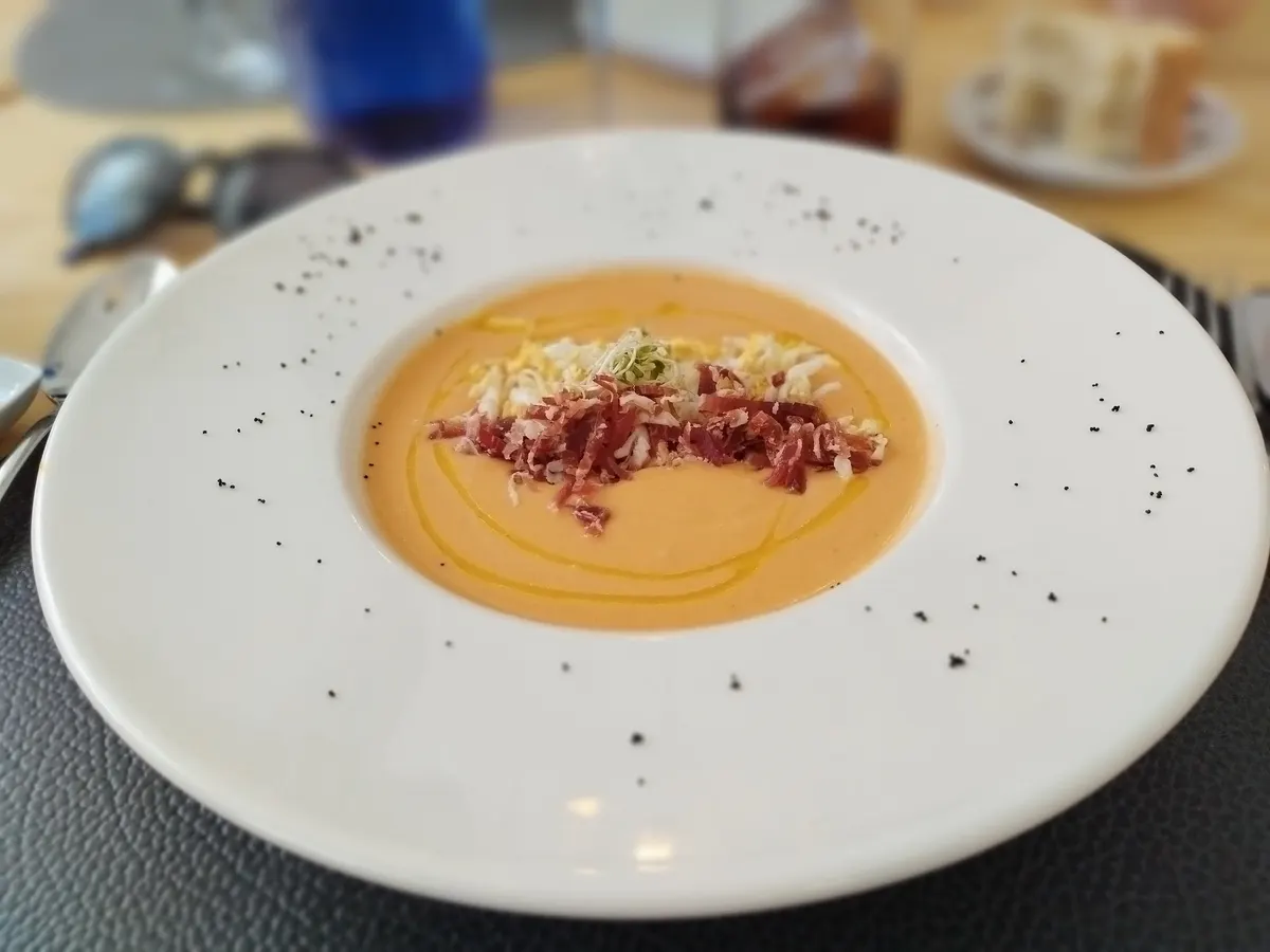 Crema fría anaranjada con virutas de jamón y huevo picado en un plato hondo blanco